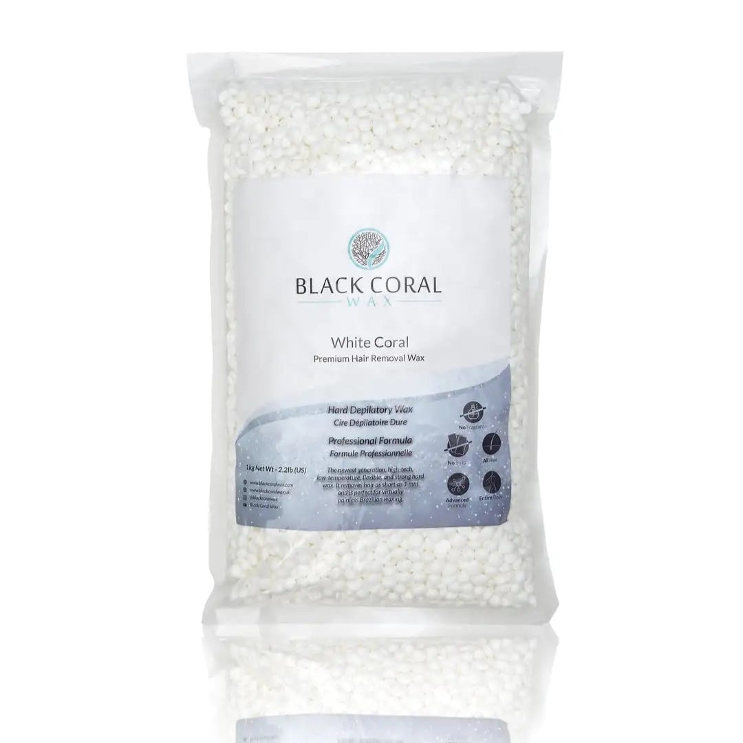 A clear plastic bag of White Coral Wax by Black Coral Wax USA, premium hard wax beads for sensitive skin, with a white and blue label, stands upright on a white background with a subtle reflection beneath.