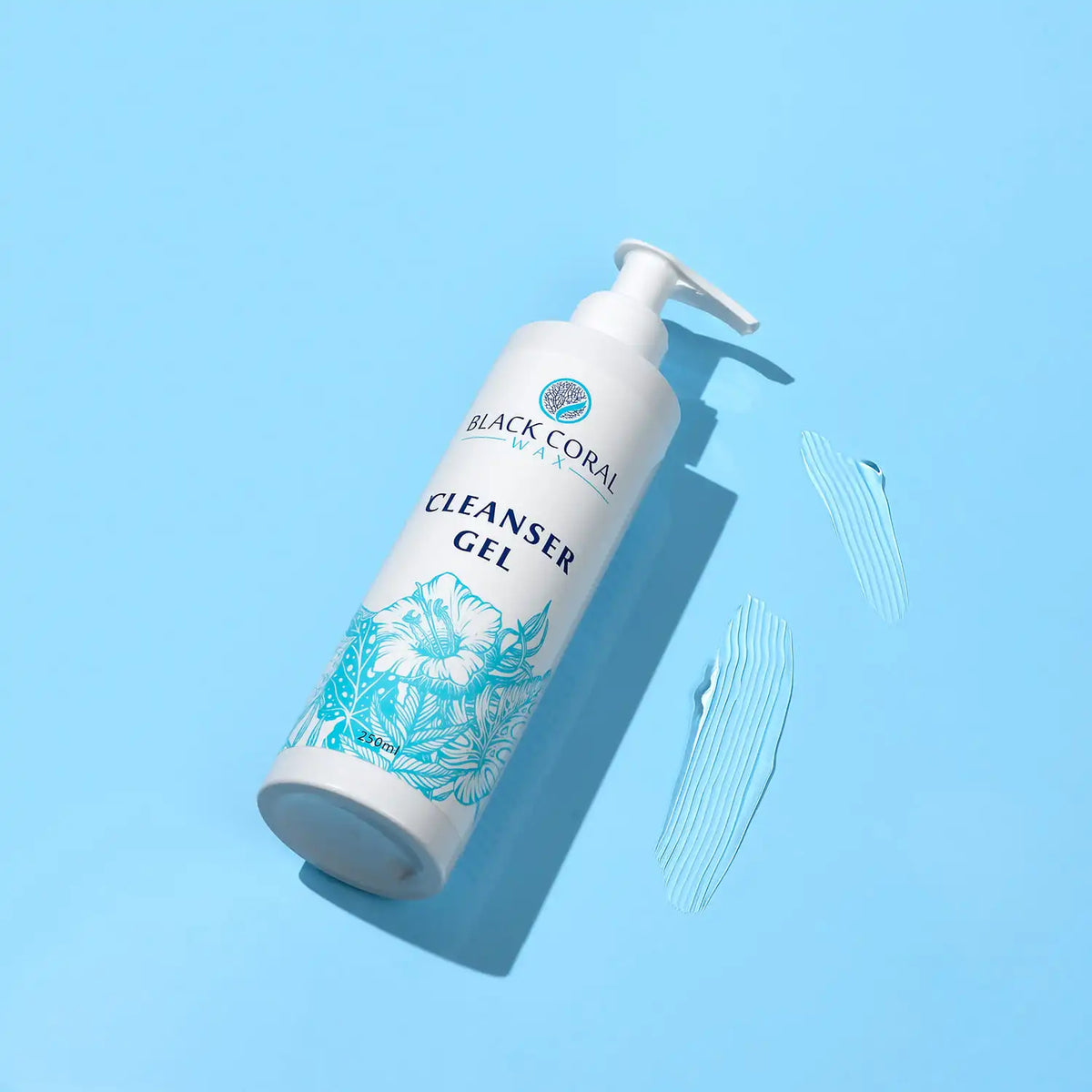 A bottle of Black Coral Wax USA Cleanser Gel 400ml with a floral design rests on a blue background, alongside two swipes of clear gel—ideal for effective pre-waxing cleansing and gentle skin preparation.