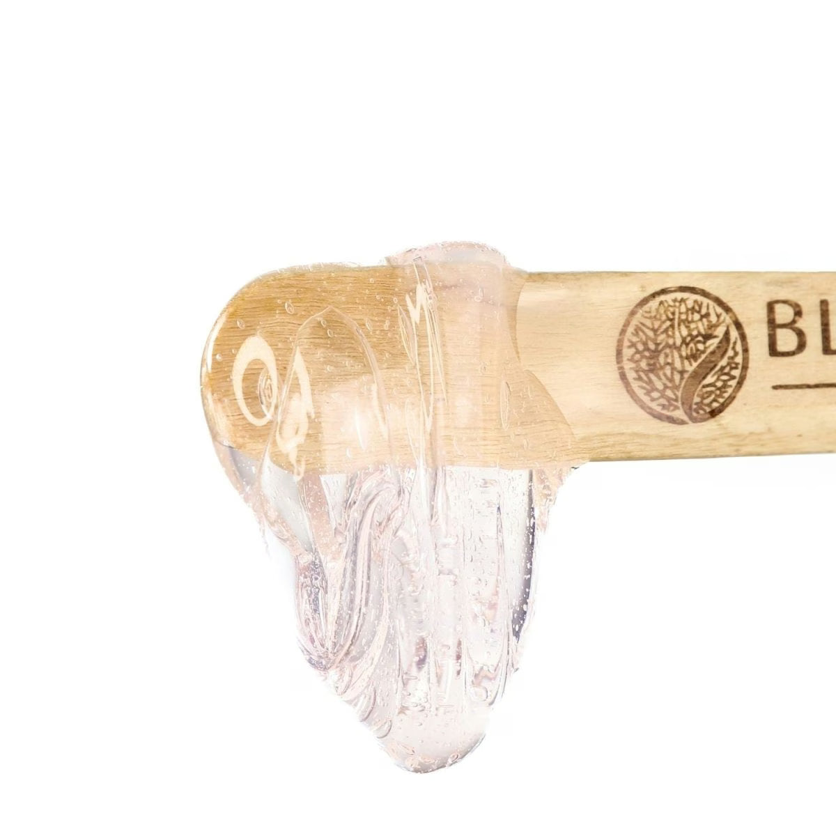 A wooden spatula with a clear, thick gel-like substance on its tip sits isolated on white, featuring a tree logo and the partial word BLU—perfect for flawless waxing using Black Coral Wax USA’s Mae Mae Waxing Kit: 5 Hard Wax Bags & Cosmetics.