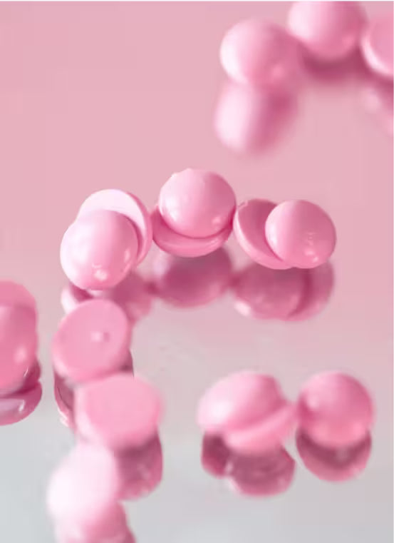 Pink round hard wax beans on a pink background