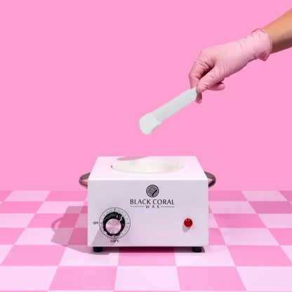 Wax warmer with a hand in a pink glove holding a spatula on a pink checkered background
