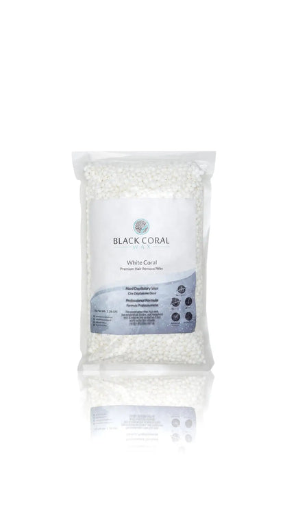 A clear plastic bag of White Coral Wax by Black Coral Wax USA, premium hard wax beads for sensitive skin, with a white and blue label, stands upright on a white background with a subtle reflection beneath.