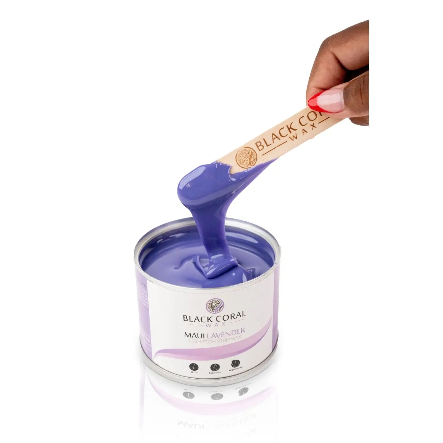 A hand holds a wooden spatula with creamy purple wax from an open tin of Maui Lavender Soft Wax by Black Coral Wax USA. The tins white and purple label, featuring lavender essential oil notes, reflects on the shiny surface below.