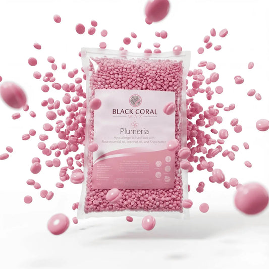 A clear bag labeled Plumeria Hard Wax by Black Coral Wax USA holds small pink stripless beads for painless hair removal, with loose pink beads scattered around the bag on a white background.