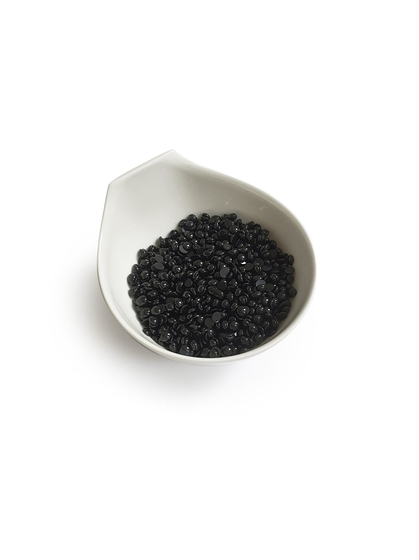 The Boss Babe Wax Glittera by Black Coral Wax USA is showcased in a white ceramic bowl akin to a Black Coral Hard Wax vessel. The bowls subtle, spout-like design elegantly cradles small, shiny black beads against a plain backdrop, reflecting potential for long-lasting hair removal.