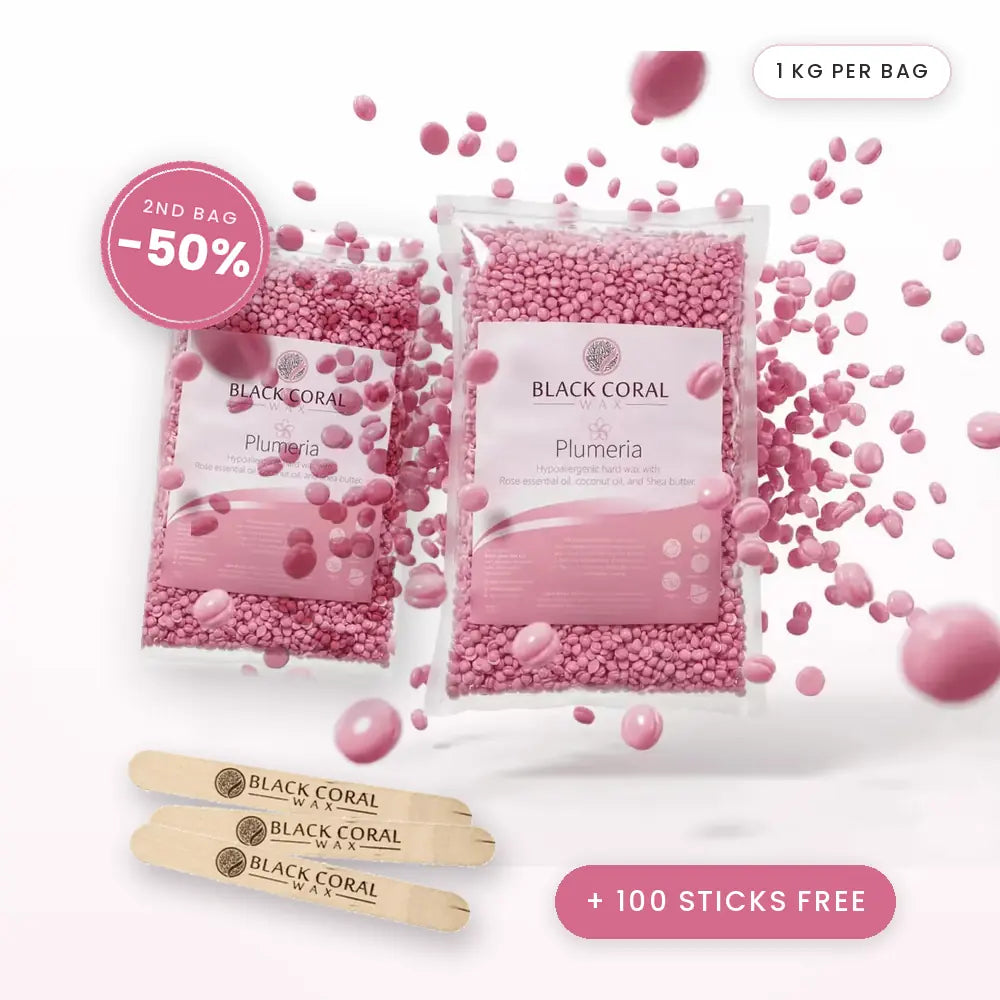 Two bags of Black Coral Wax USA AT-HOME KIT - Plumeria Hard Wax are surrounded by loose beads, with three wooden spatulas displayed below. A “2nd bag -50%” badge is shown. Text reads: 1 kg per bag and +100 sticks free—perfect for sensitive skin waxing with premium hot wax beads from Black Coral Wax USA.